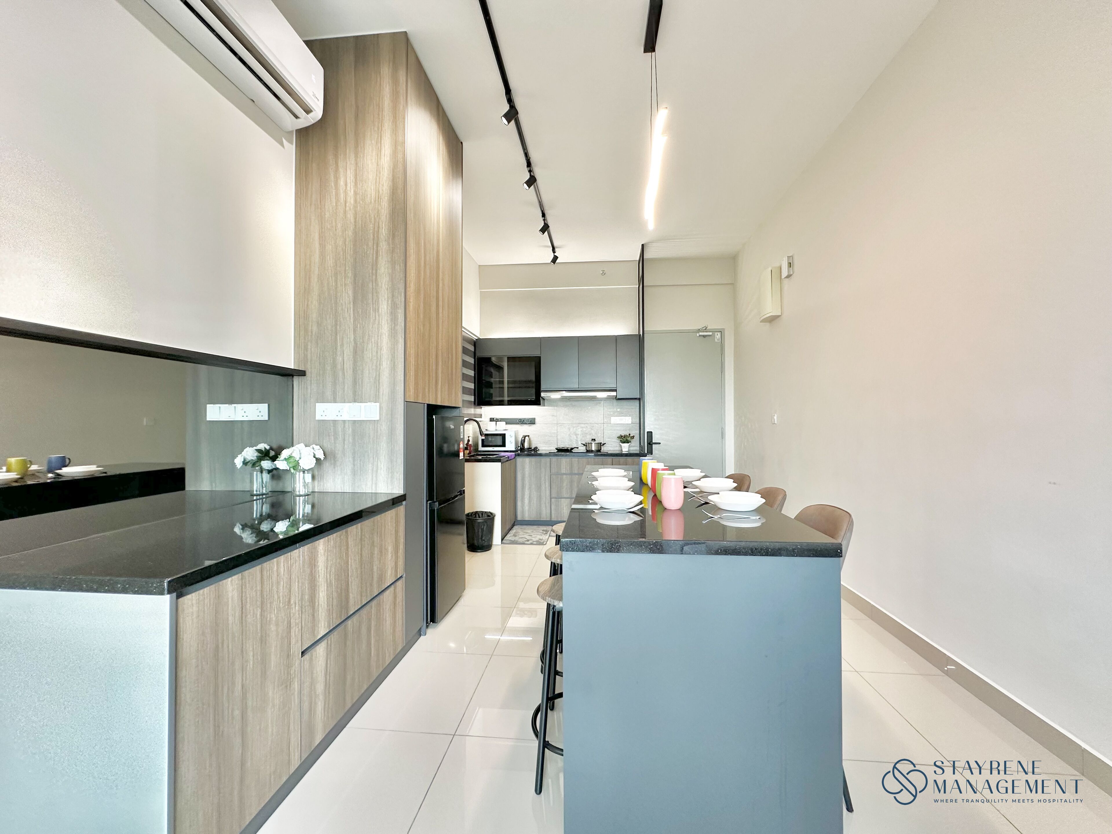 A modern kitchen with a central island, built-in appliances, and a dining area with chairs.