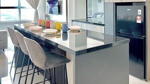 A modern kitchen with a central island, a ceiling fan, and a refrigerator. - Amber Cove Melaka Sea View by Stayrene (Malacca City)