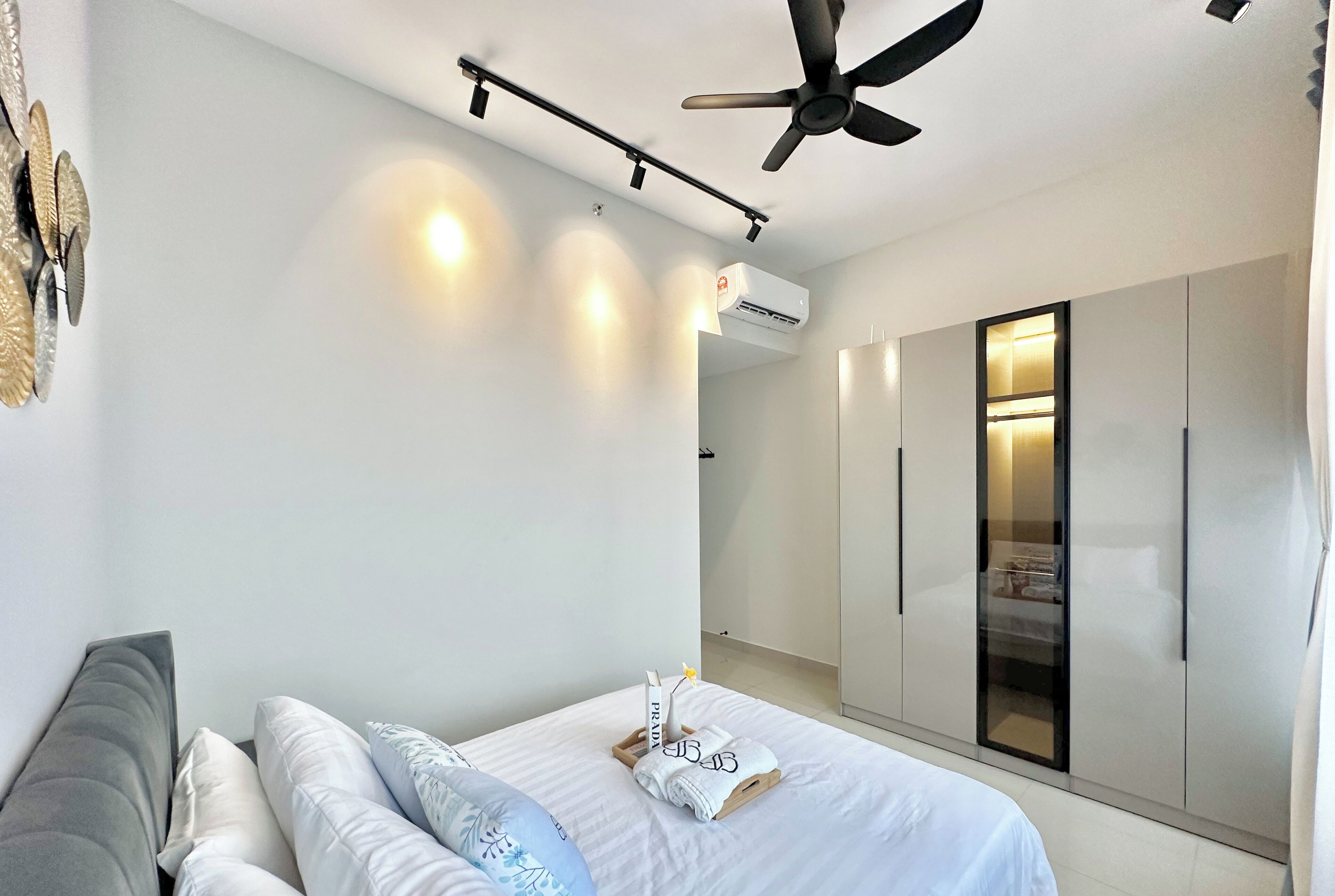 A modern bedroom with a bed, a ceiling fan, and a wardrobe.