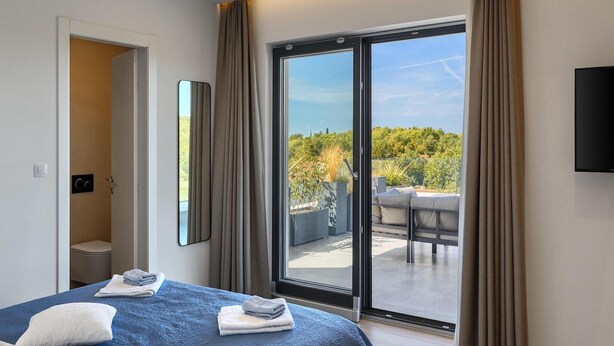 Ein Hotelzimmer mit Bett, Bad und Balkon mit Blick auf Grünflächen.