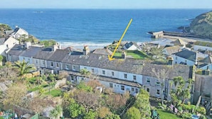 Zona residencial costera con casas, una vista despejada del mar y una flecha amarilla señalando una casa en particular.