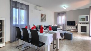 A modern dining area with a table set for four, a sofa, a TV, and a fireplace. - Awesome home in Barban (Barban)
