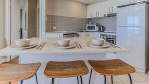 A modern kitchen with a central island, white cabinets, and a stainless steel refrigerator.