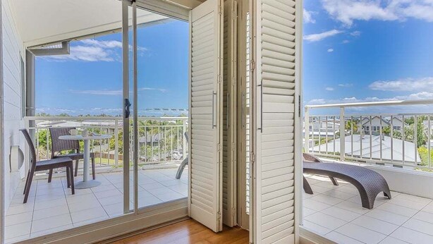 A balcony with a view of the city, a sliding glass door, and a small outdoor seating area.