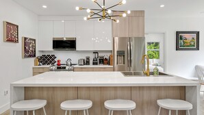 Een moderne keuken met een groot schiereiland, roestvrijstalen apparatuur en een bijzondere kroonluchter.