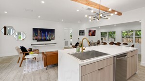 A modern kitchen with a central island, stainless steel appliances, and a dining area with a large window. - Havana House ~ Miami LUXE ~ West Brickell (Miami)
