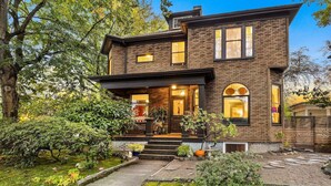 A two-story brick house with a front porch, steps leading up to the entrance, and a small garden with a pathway. - Artistic Victorian Gem in a Trendy neighborhood (Portland)