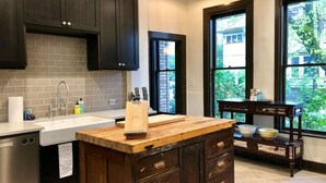 A kitchen with dark wooden cabinets, a white sink, and a wooden island with drawers. - Artistic Victorian Gem in a Trendy neighborhood (Portland)
