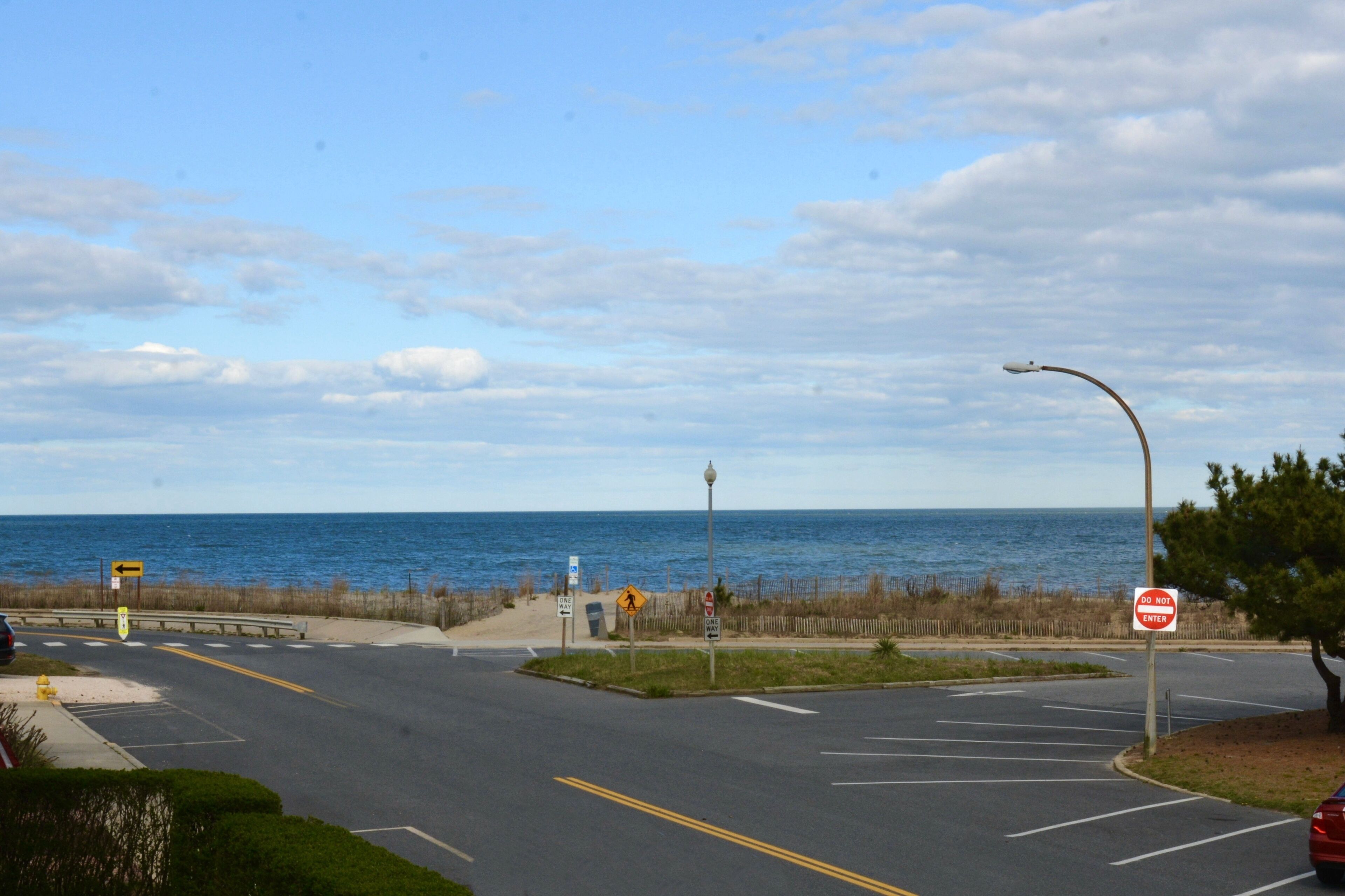 Ein Küstenstraßen-Kreuzung mit einem 'Do Not Enter'-Schild, einem Fußgängerüberweg und Blick aufs Meer.