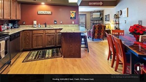 A kitchen with wooden cabinets, a granite countertop, and a dining area with a table and chairs.