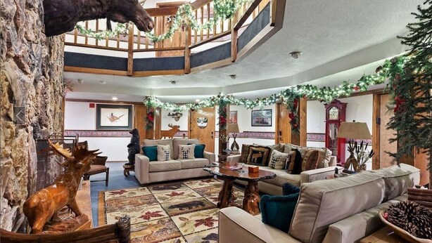 A multi-level interior with a central staircase, wooden decor, and festive decorations.