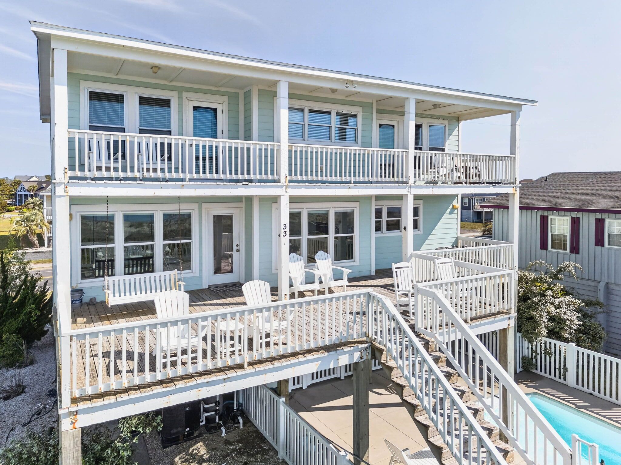 A two-story house with a balcony, a pool, and a covered patio area.