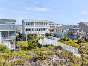 A beachfront property with multiple buildings, including a two-story house with a balcony and a separate building with a pool.