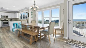 A spacious kitchen with a dining area, large windows, and a view of the ocean. - Zion of Holden by Brunswick Vacation Rentals: 5BR Oceanfront w/ Pool & Views (Holden Beach)