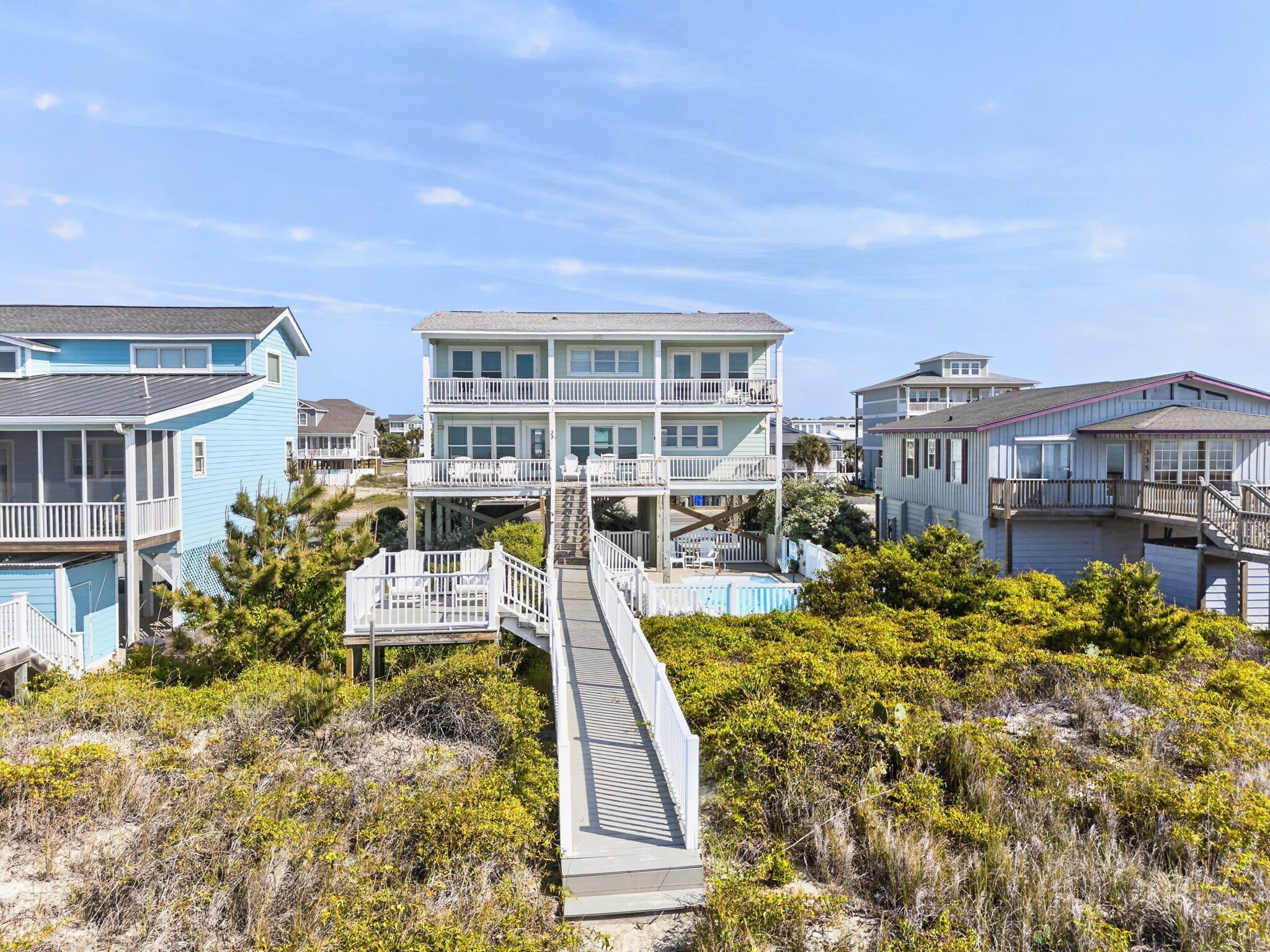 Un quartier résidentiel situé sur la côte, avec des immeubles à plusieurs étages, une promenade en bois et une piscine.