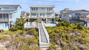 A coastal residential area with multi-story houses, a wooden walkway, and a pool. - Zion of Holden by Brunswick Vacation Rentals: 5BR Oceanfront w/ Pool & Views (Holden Beach)