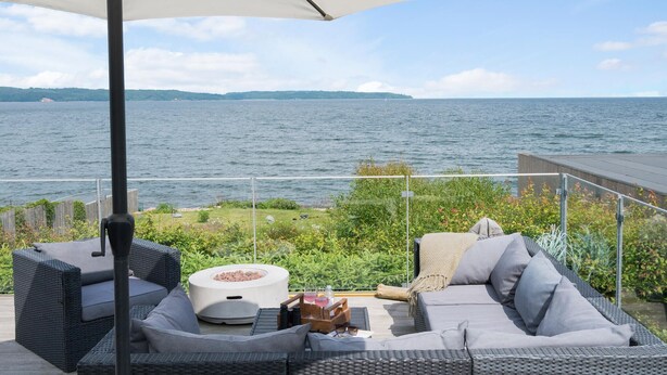 Una terraza con mobiliario exterior, un brasero y vista al mar.