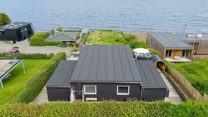 Una casa moderna con techo plano, ventanas grandes y vista al mar.