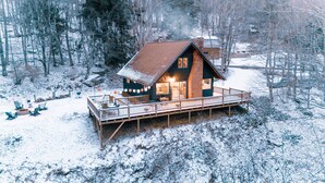 Eine Hütte mit einer Terrasse, umgeben von schneebedeckten Bäumen.