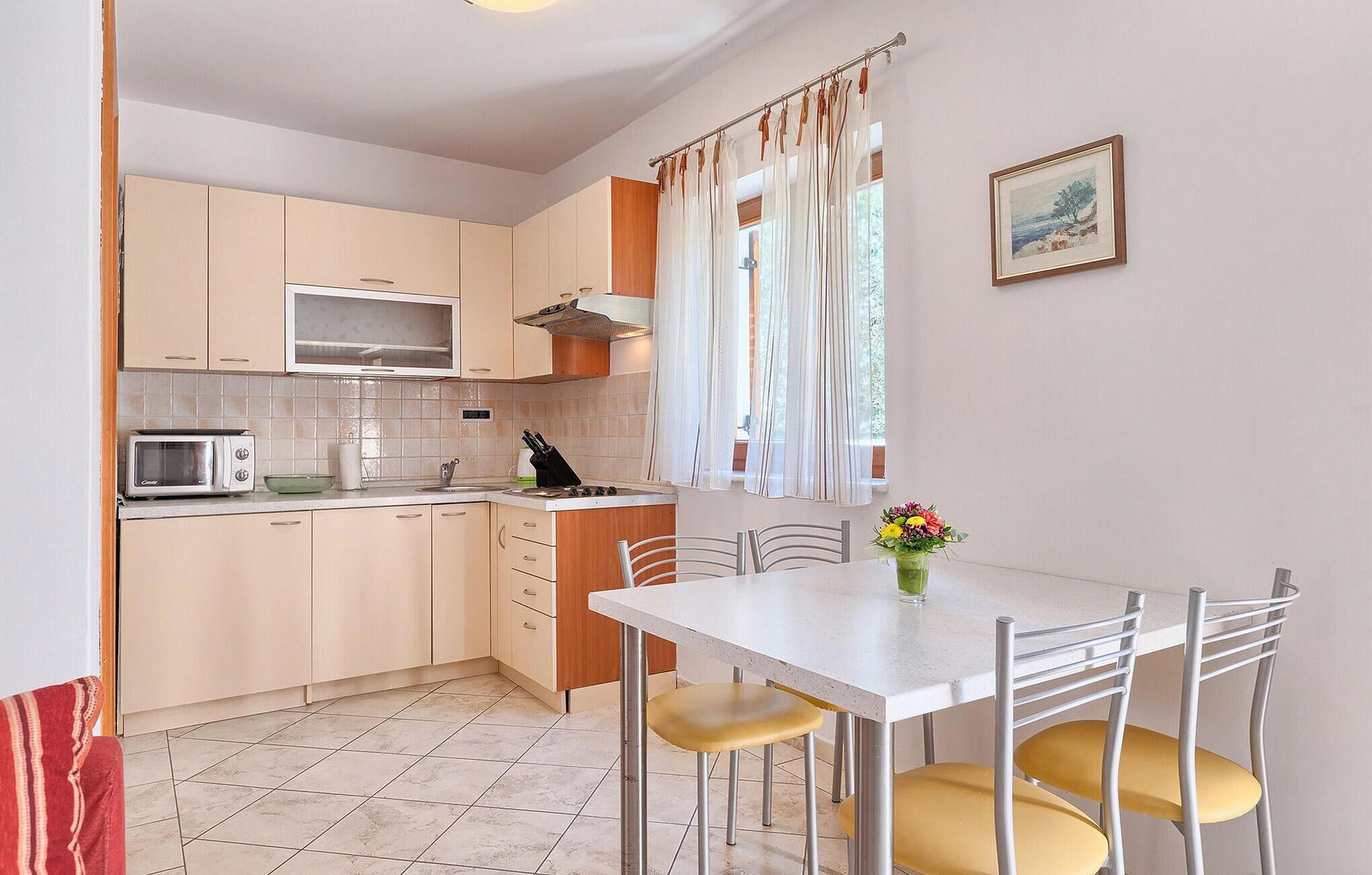 A compact kitchen with a microwave, sink, and dining area with chairs.