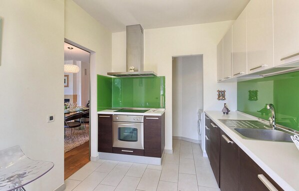 Une cuisine moderne dotée d’un îlot central, d’un four encastré et d’un crédence de couleur verte.