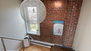 Een trap die leidt naar een eetgedeelte met een bakstenen muur, een hangende lamp en een ingelijste foto.