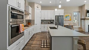 A modern kitchen with white cabinets, stainless steel appliances, and a central island. - The Liftview: 3BR home at Purgatory Resort (Durango)