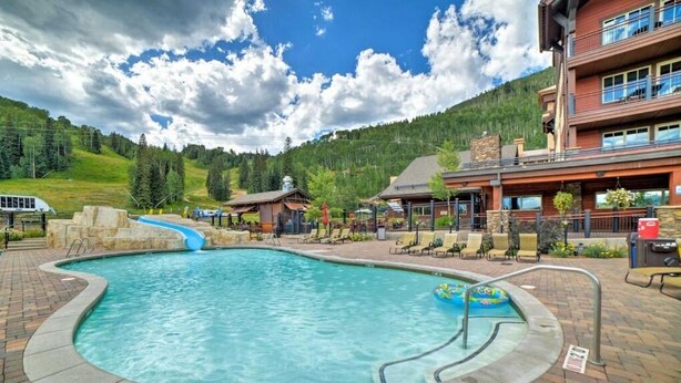 A pool area with a water slide, lounge chairs, and a building with multiple balconies. - The Liftview: 3BR home at Purgatory Resort (Durango)