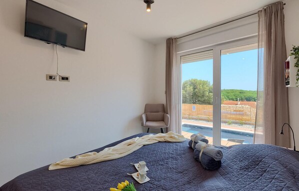 A bedroom with a bed, a chair, a TV, and a view of the outdoors. - Pet friendly home in Pula (Pula)