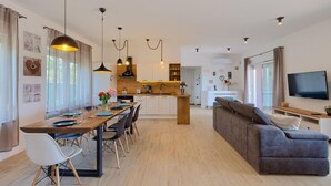 A modern kitchen with a dining area, a sofa, and a TV. - Pet friendly home in Pula (Pula)