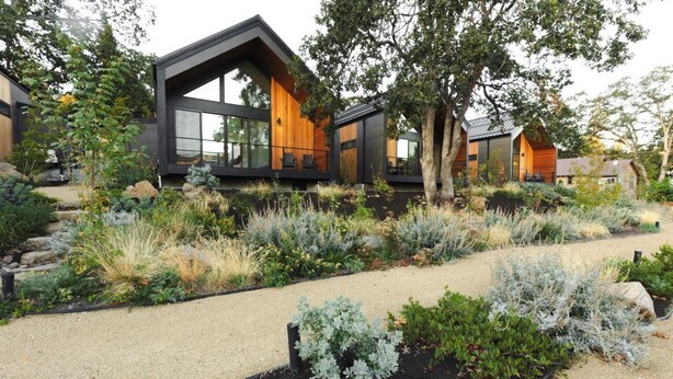 Una casa moderna con amplios ventanales y un jardín cuidado.
