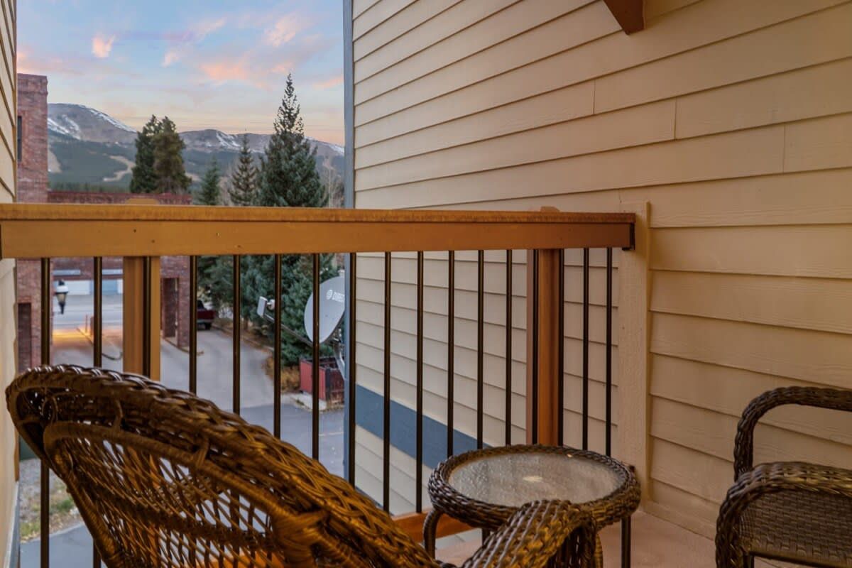 A balcony with wicker furniture and a view of a mountain landscape.