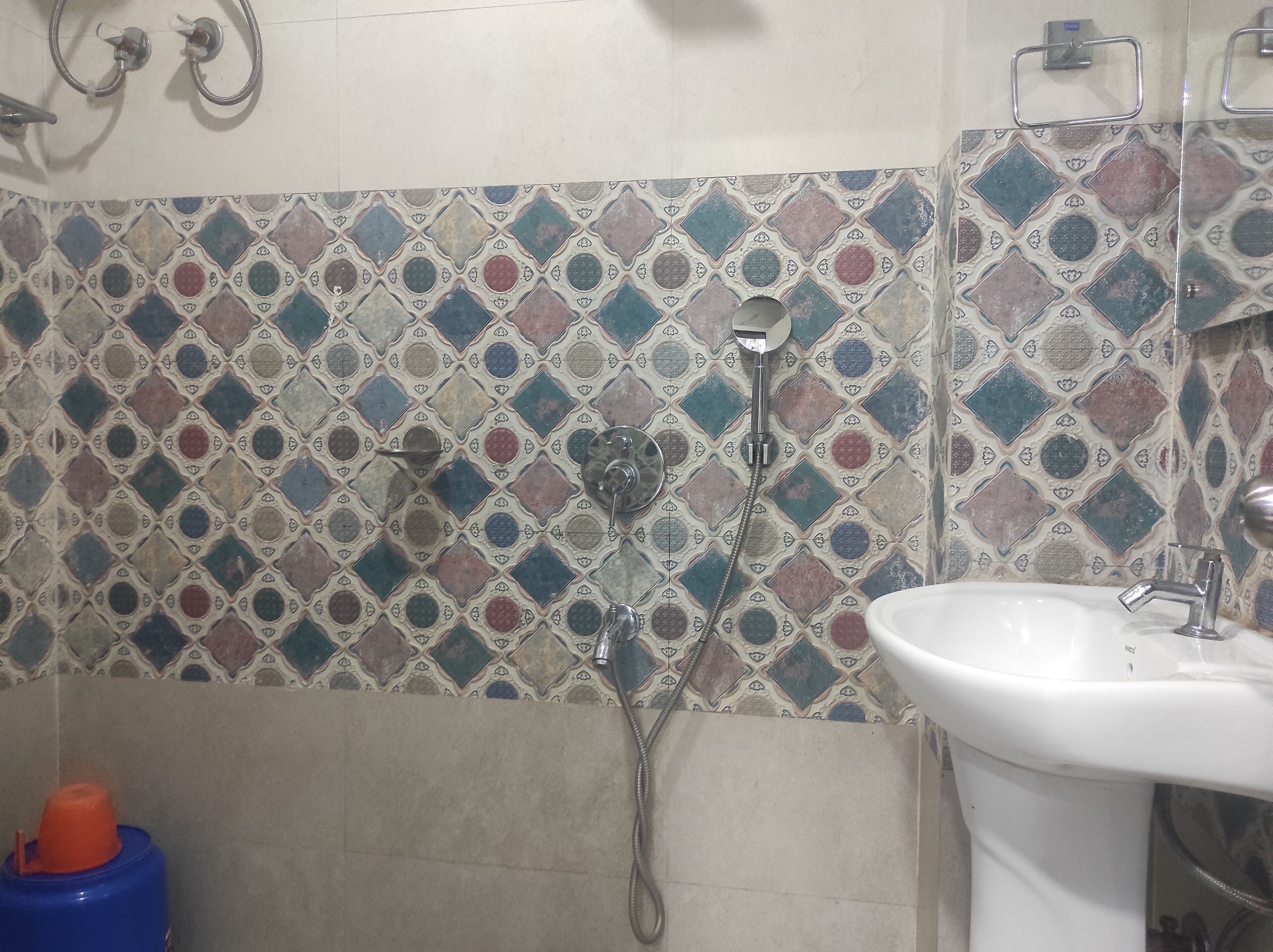 Un baño con pared de ducha enlosetada, un lavamanos blanco y un dispensador de agua azul.
