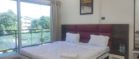 Un dormitorio con una cama grande, vistas a un balcón y un cuadro en la pared.