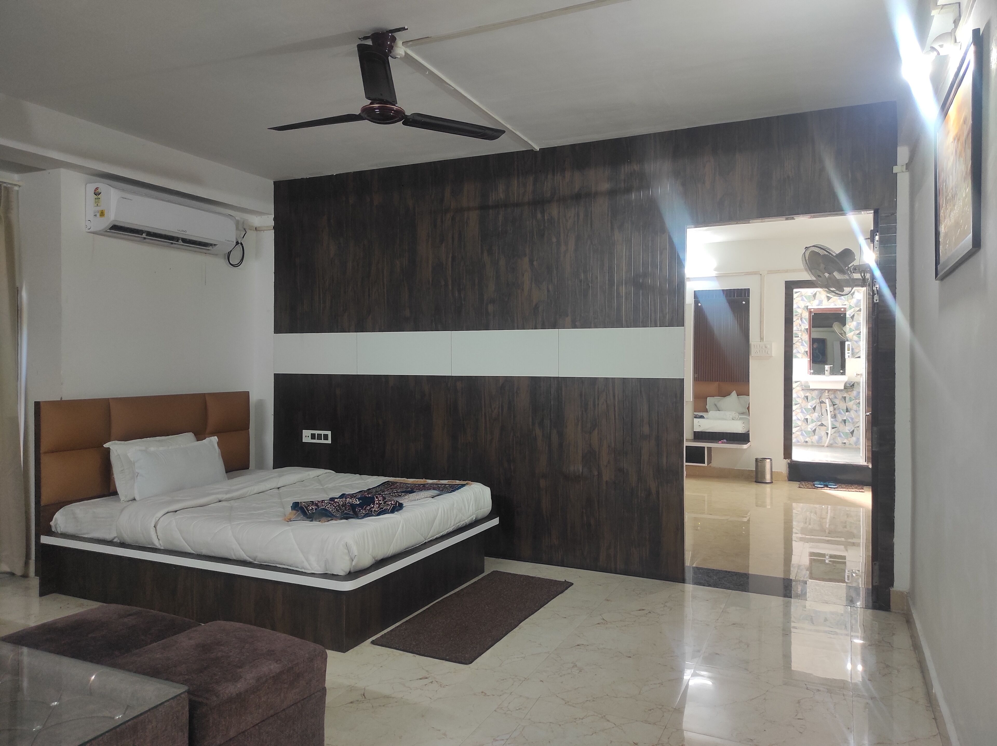 Un dormitorio moderno con una cama grande, un ventilador de techo y vistas al baño.