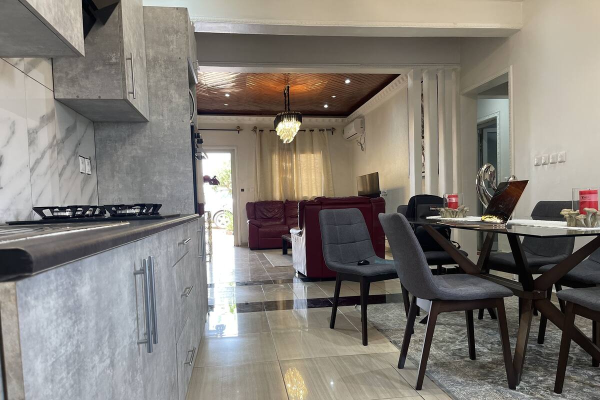 A modern kitchen with a marble countertop, a built-in stove, and a dining area with a table and chairs.