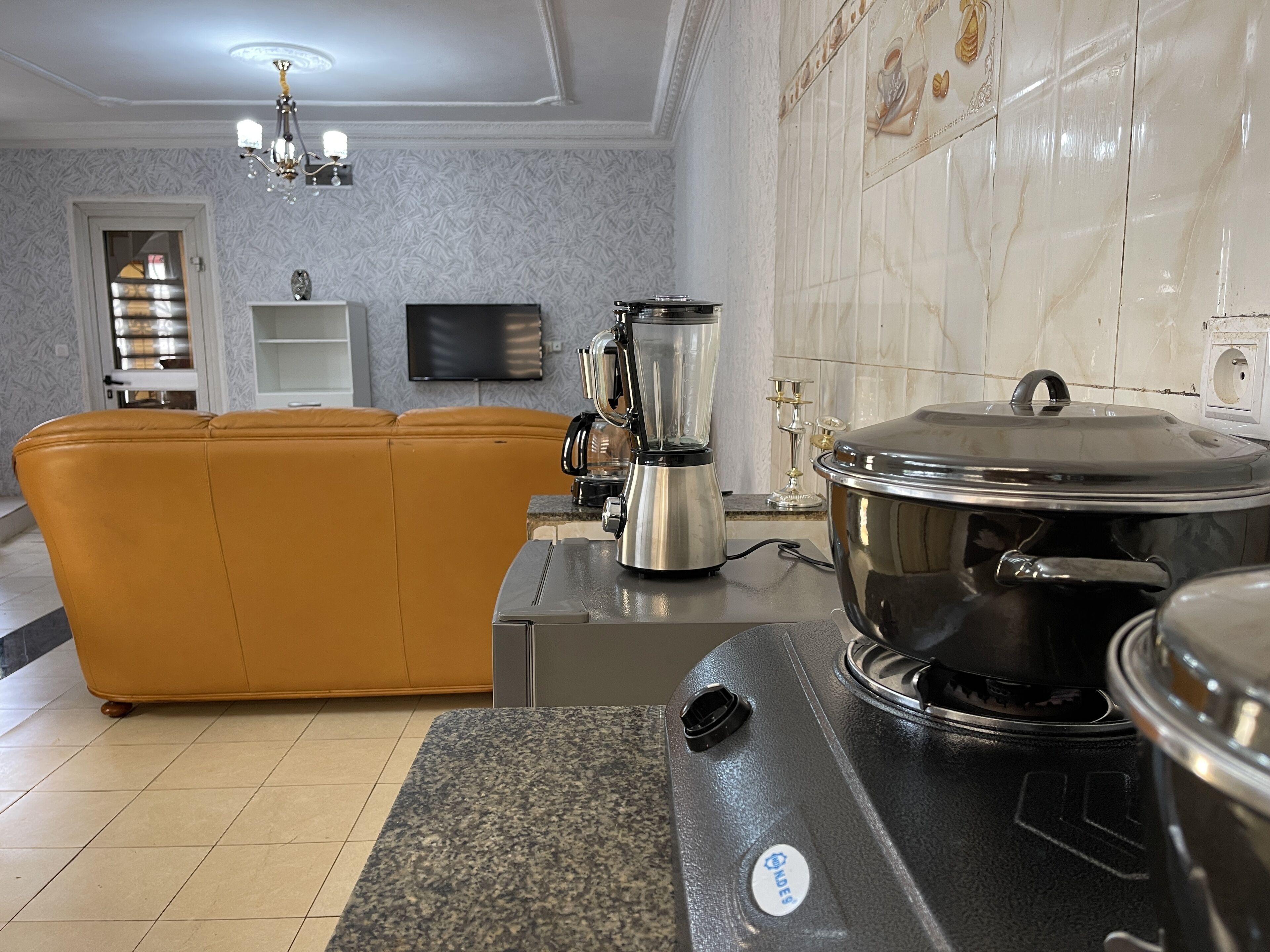 A modern kitchen with a gas stove, a coffee maker, and a large pot on the counter.
