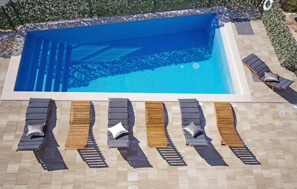 A swimming pool with adjacent sun loungers and a tiled deck. - Amazing home in Makarska (Makarska)