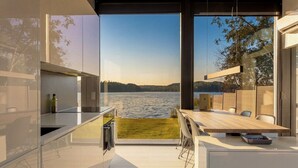 Eine moderne Küche mit Seeblick, eine Essecke mit Stühlen und ein großer Esstisch.