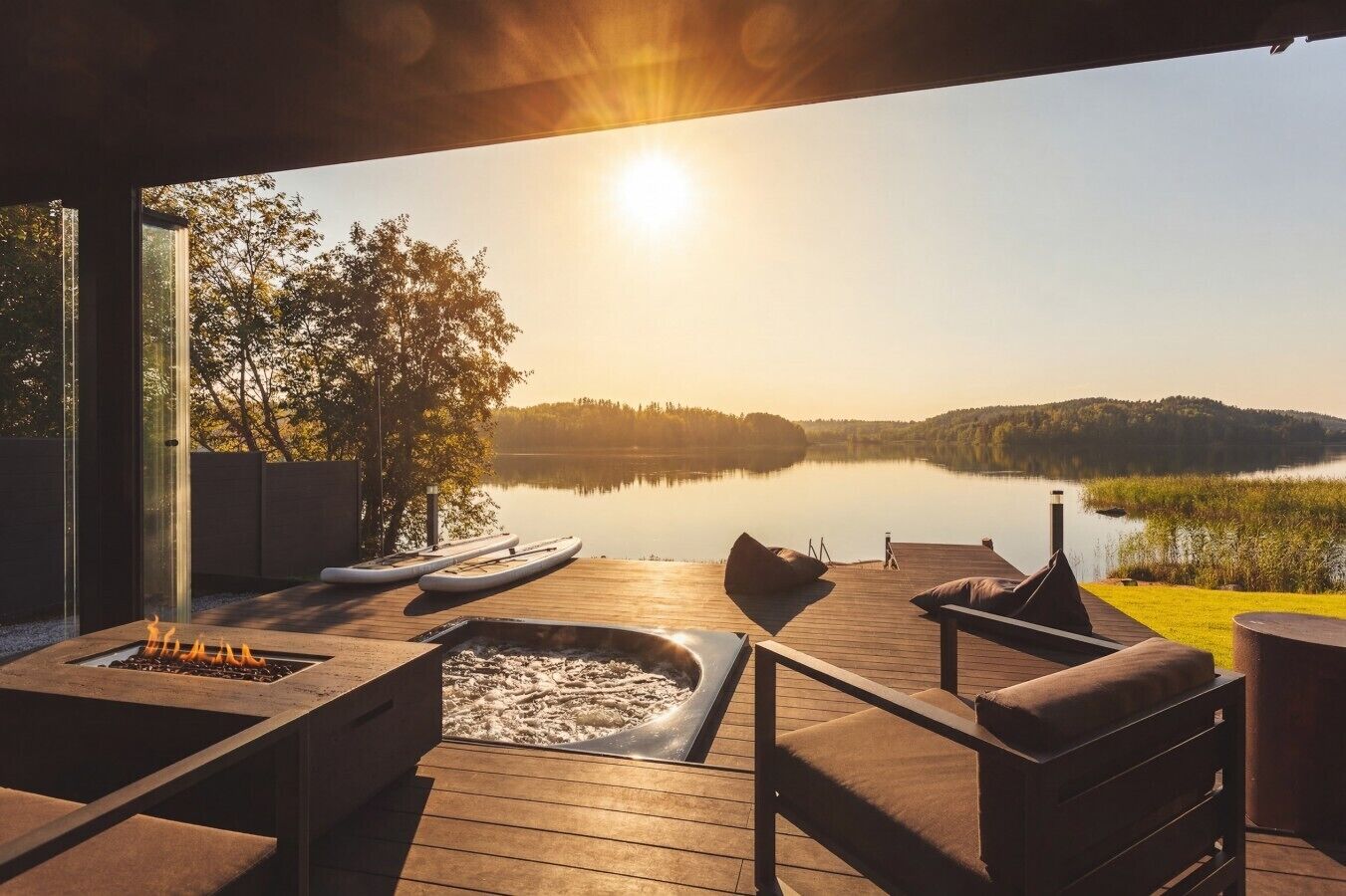 Eine Terrasse mit Sitzgelegenheit, einem Feuerkorb und Blick auf einen See bei Sonnenuntergang.