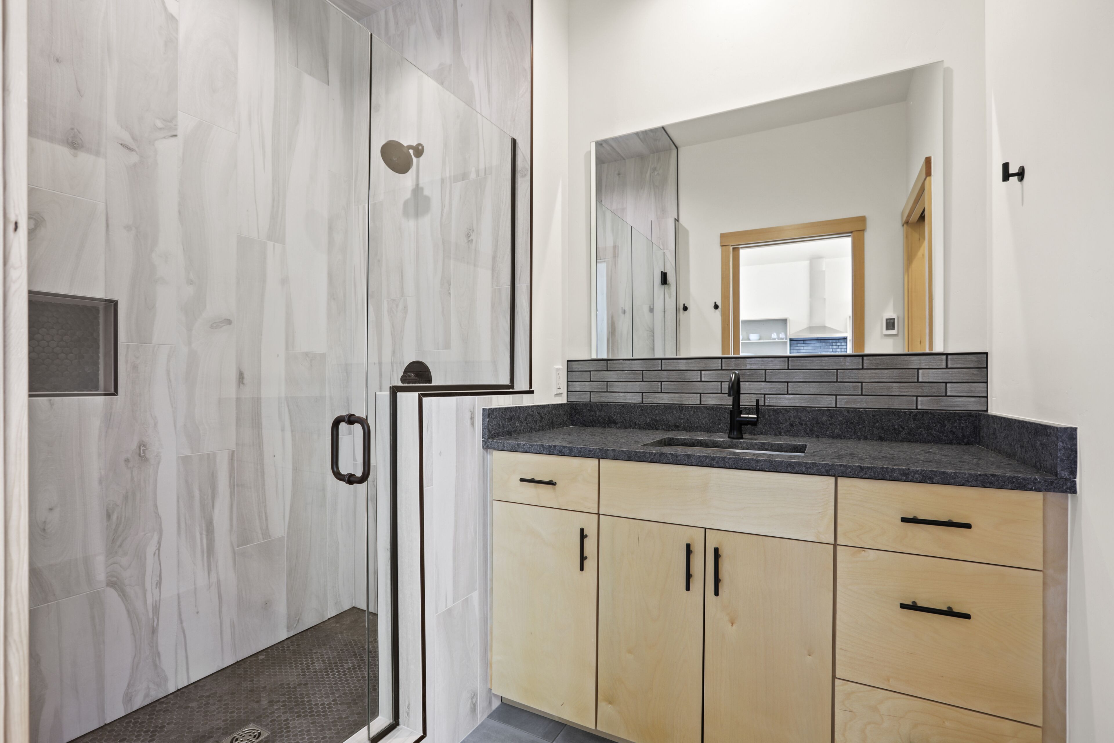 A modern bathroom with a shower, a sink, and wooden cabinets.