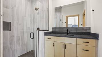 A modern bathroom with a shower, a sink, and wooden cabinets.