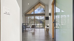 Una habitación amplia con techo alto, ventanas grandes y vistas al exterior.