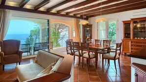 A spacious living area with a balcony overlooking the sea, a dining table with chairs, and a wooden cabinet with glass doors. - Beach front home in Moscenicka Draga with WiFi (Moscenicka Draga)