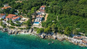An aerial view of a coastal residential area with multiple houses, a clear blue sea, and rocky terrain. - Beach front home in Moscenicka Draga with WiFi (Moscenicka Draga)