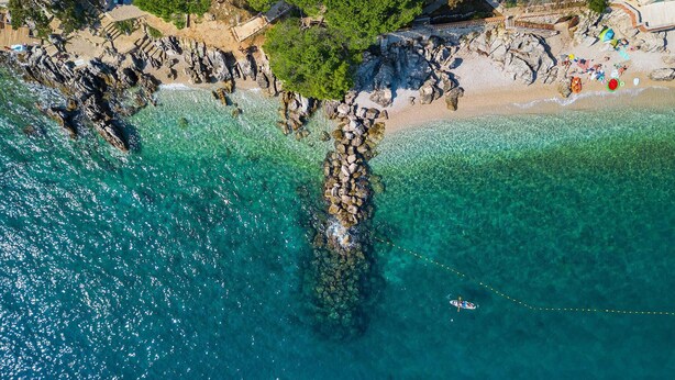 An aerial view of a coastal area with clear turquoise waters, rocky formations, and a sandy beach. - Beach front home in Moscenicka Draga with WiFi (Moscenicka Draga)