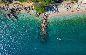An aerial view of a coastal area with clear turquoise waters, rocky formations, and a sandy beach. - Beach front home in Moscenicka Draga with WiFi (Moscenicka Draga)