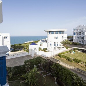 A coastal hotel with a view of the sea, featuring a modern architecture with a central tower and multiple balconies.