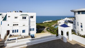 Zona residencial costera con edificios blancos, vista despejada al mar y un paseo pavimentado.
