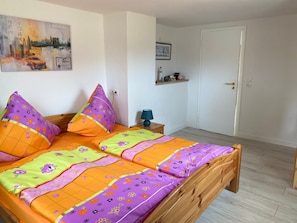 Uma cama com roupa de cama estampada com flores, cabeceira de madeira e mesa de cabeceira com abajur.